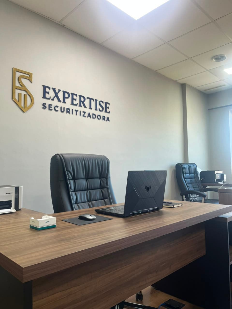 Recepção da Expertise Securitizadora, com a logomarca em relevo dourado e azul aplicada na parede
